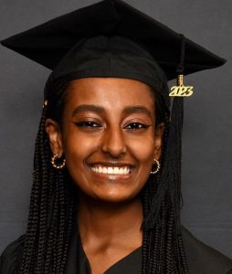 Headshot of Belane smiling at the camera in her black graduation cap and gown.